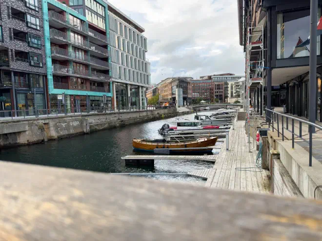 Small boats moored along an Oslo canal between modern waterfront buildings